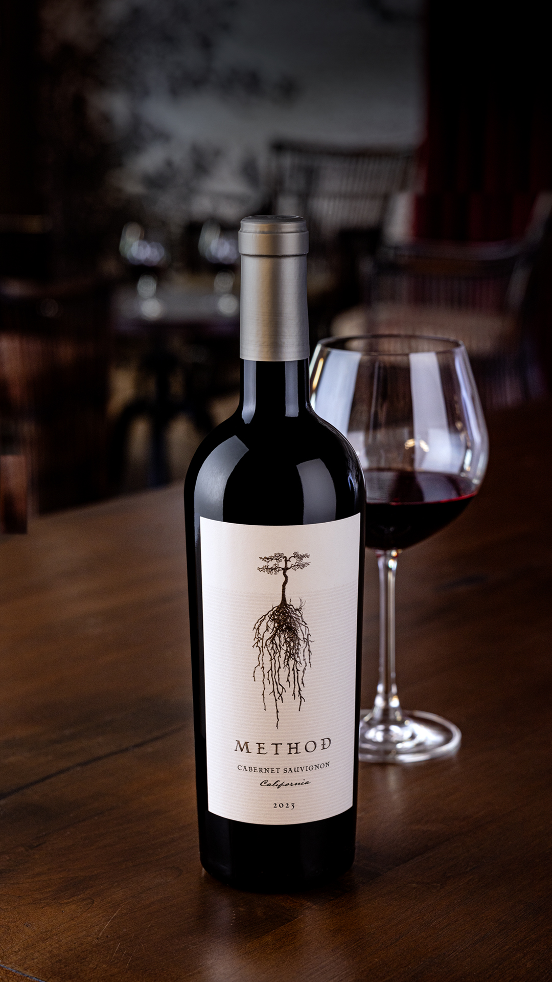 Method California Cabernet Sauvignon 2023 beside a glass of wine on a dark wooden table